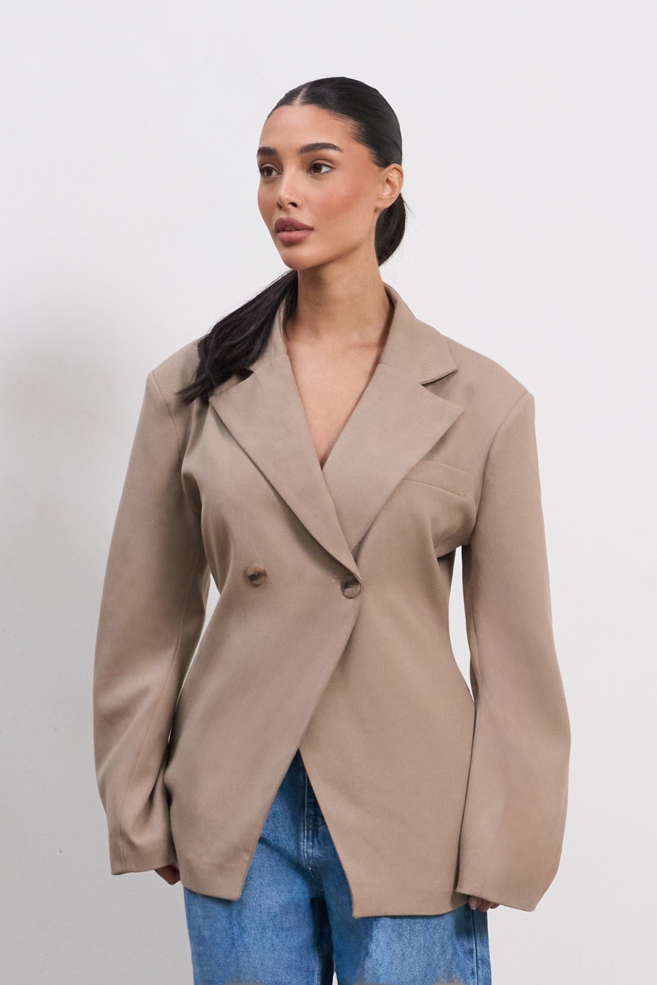 Woman wearing a beige blazer over a blue top on a white background