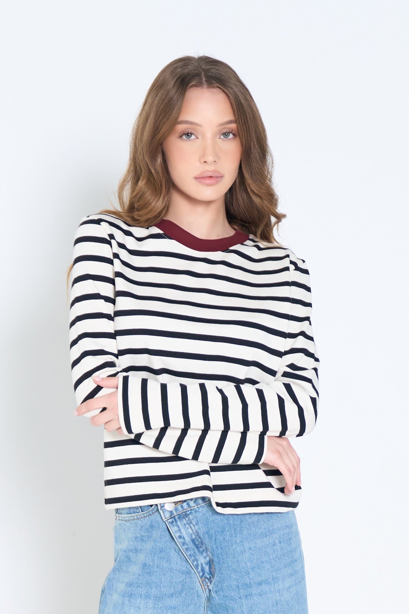 Woman wearing a black and white striped sweater with a maroon collar against a white background